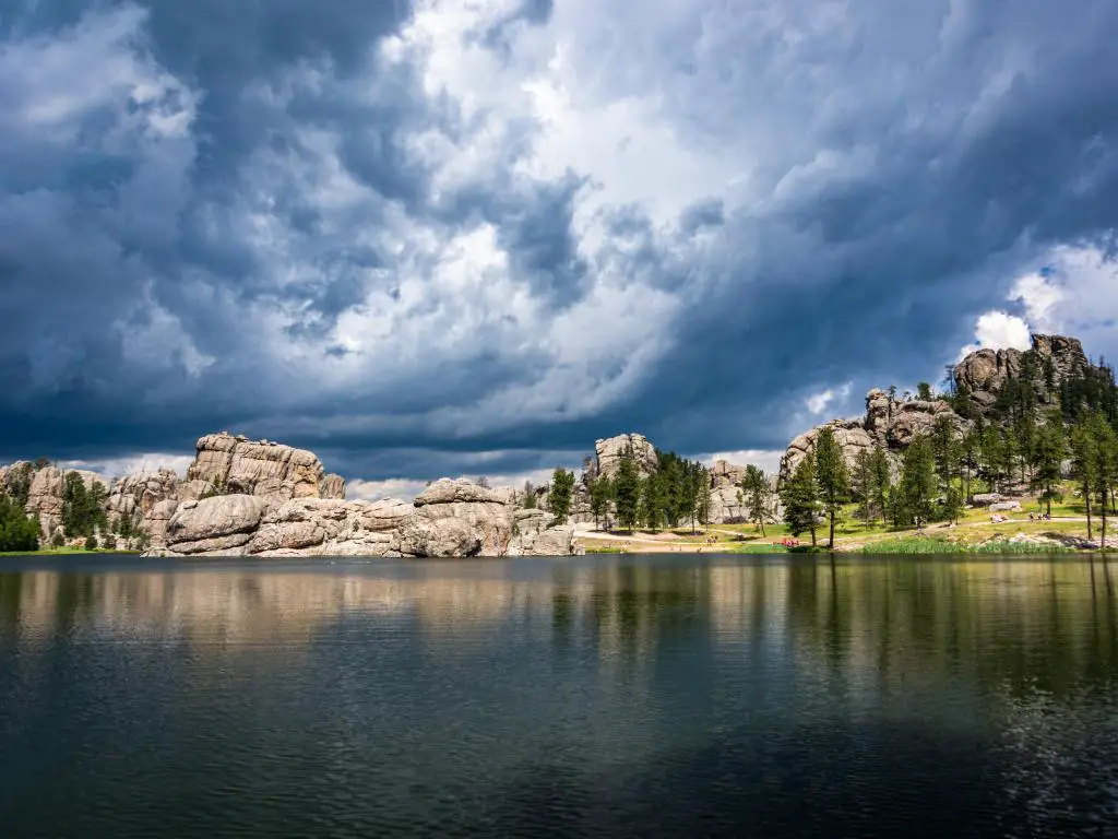 Custer State Park, Dakota del Sur con nubes de tormenta rodando sobre Sylvan Lake, con formaciones rocosas en la distancia y árboles. 
