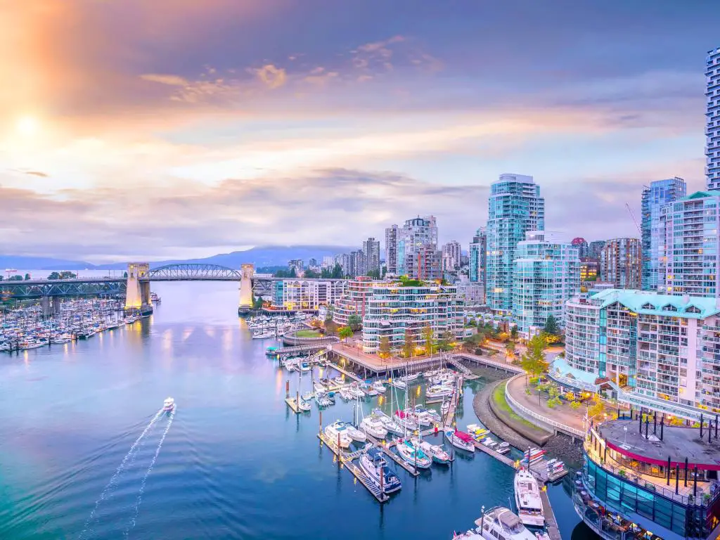 Horizonte de Vancouver, Columbia Británica, Canadá al atardecer con barcos en el puerto y montañas a lo lejos. 