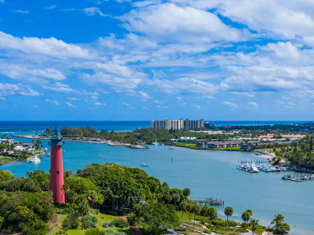 Faro de la isla de Júpiter, condado de Palm Beach, Florida, con una toma aérea sobre el faro rojo de la isla de Júpiter, rodeado por el mar y las islas cubiertas de árboles. 