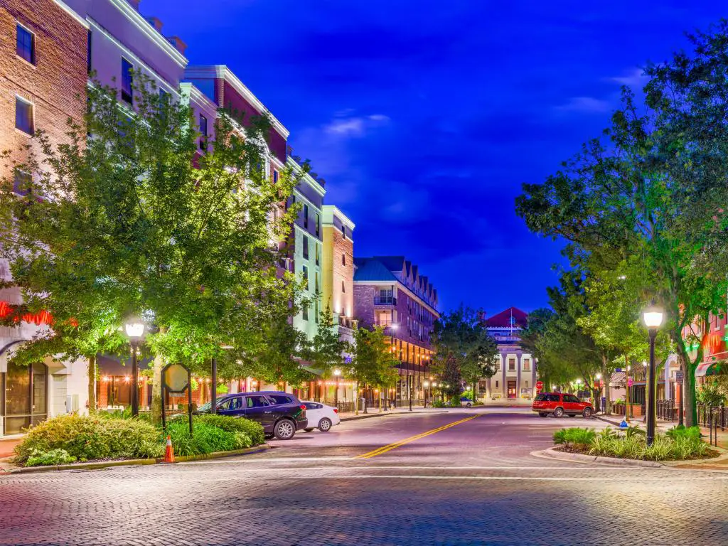 El centro de Gainesville, Florida, EE.UU. al atardecer, con calles arboladas y edificios de hermosos colores.