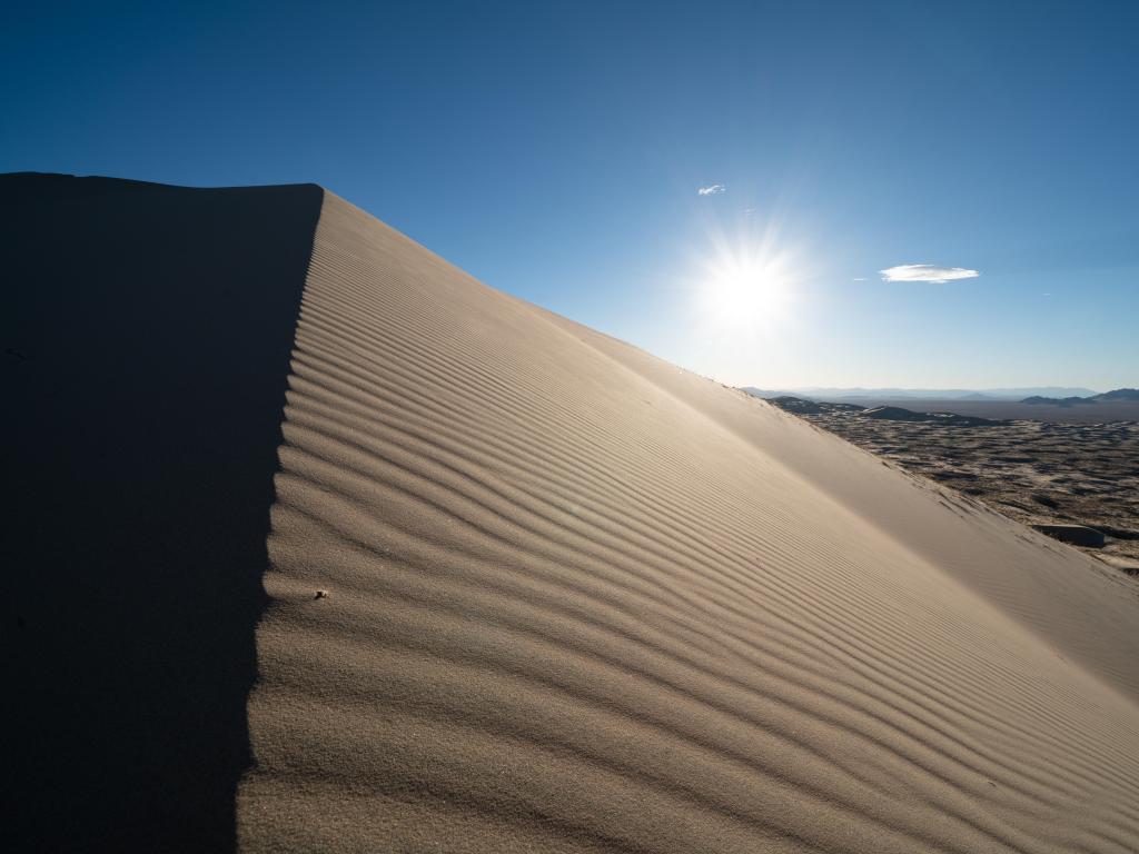 Duna de arena masiva con sol brillando desde atrás