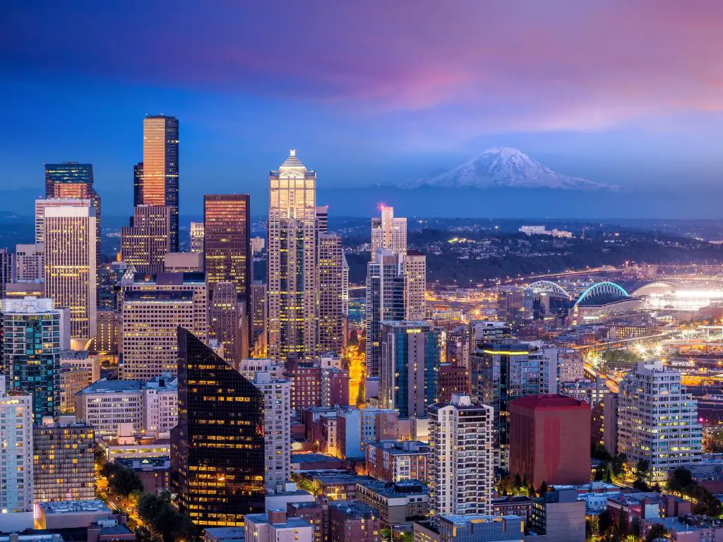 Seattle, Estados Unidos con el horizonte de la ciudad al atardecer y el tenue contorno de una montaña en la distancia.