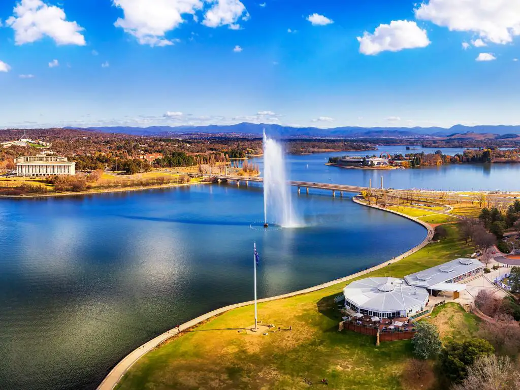 Canberra, Australia con el lago Burley Griffin rodeado por la ciudad en un día soleado entre las colinas circundantes.