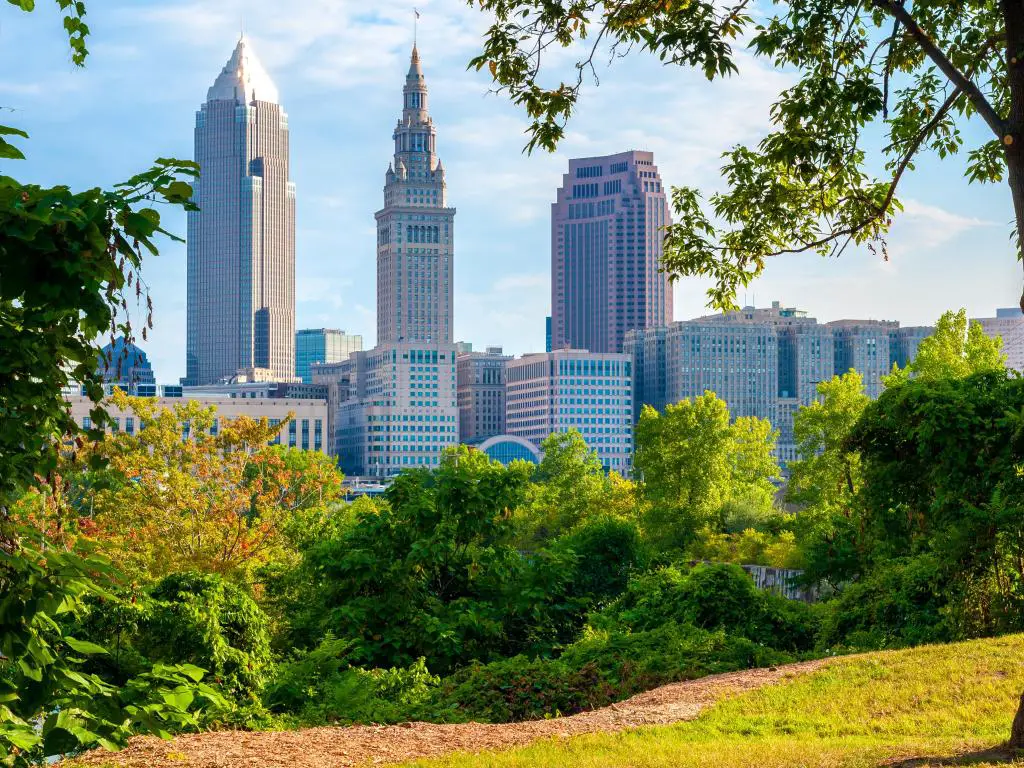 Cleveland, Ohio, con vistas al centro de la ciudad a lo lejos desde un pequeño parque a la luz de la mañana, enmarcado por árboles y césped en primer plano.