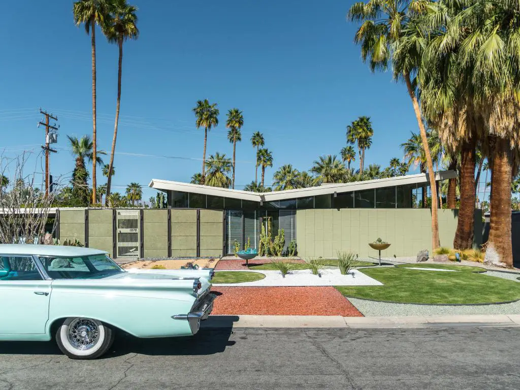 Un automóvil antiguo estacionado afuera de una casa residencial de mediados de siglo en Palm Springs