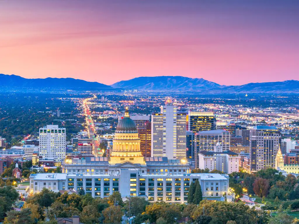 Salt Lake City, Utah, EE.UU. con el horizonte del centro de la ciudad en primer plano y las montañas en la distancia al atardecer con un hermoso cielo rojo