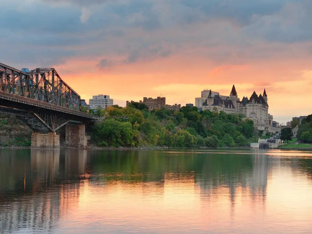 El horizonte de la ciudad de Ottawa al amanecer en la mañana sobre el río con edificios históricos urbanos y nubes coloridas