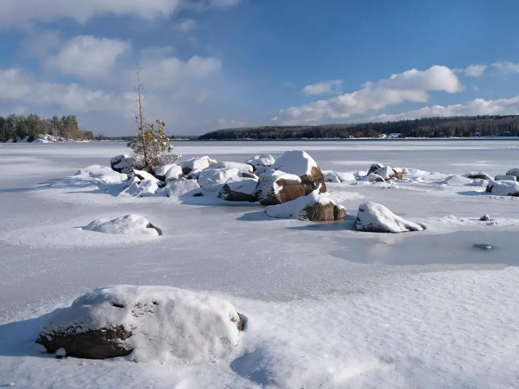 Una escena invernal de grandes rocas de granito cubiertas de nieve rodeadas por el hielo que se forma en el lago Lower Buckhorn, en Kawarthas, Ontario.