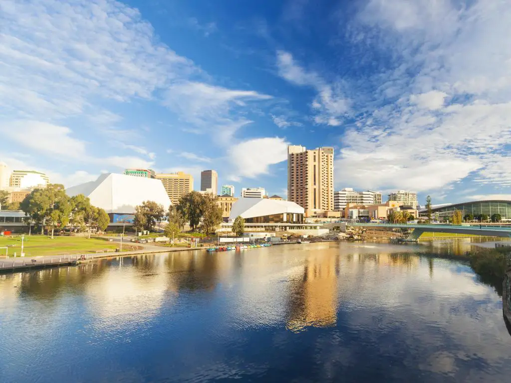 Adelaide, Australia, que muestra el área del centro de la ciudad al fondo y el agua en primer plano en un día soleado con cielo azul.