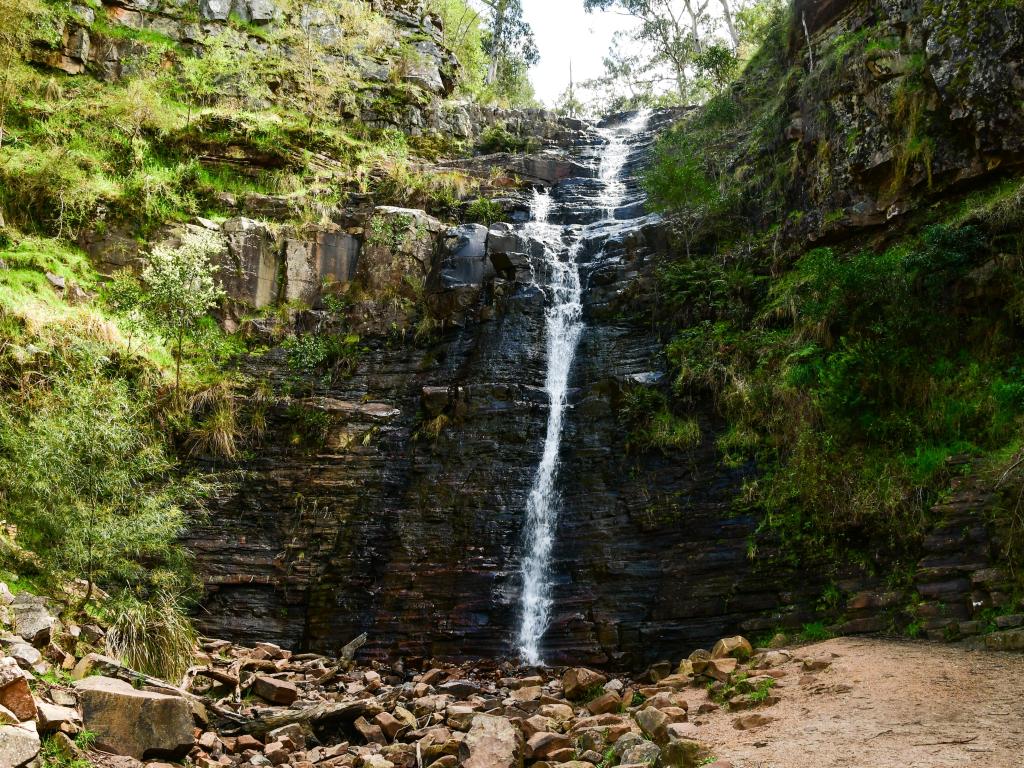 Parque Nacional Grampians, Australia con una cascada en el centro y rodeada de rocas y follaje verde.