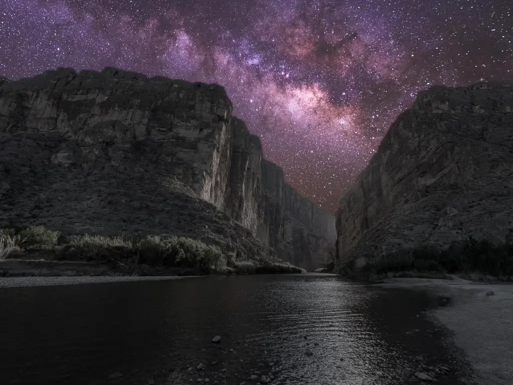 Altos acantilados con un gran río en el fondo, de noche, con muchas estrellas en el cielo nocturno