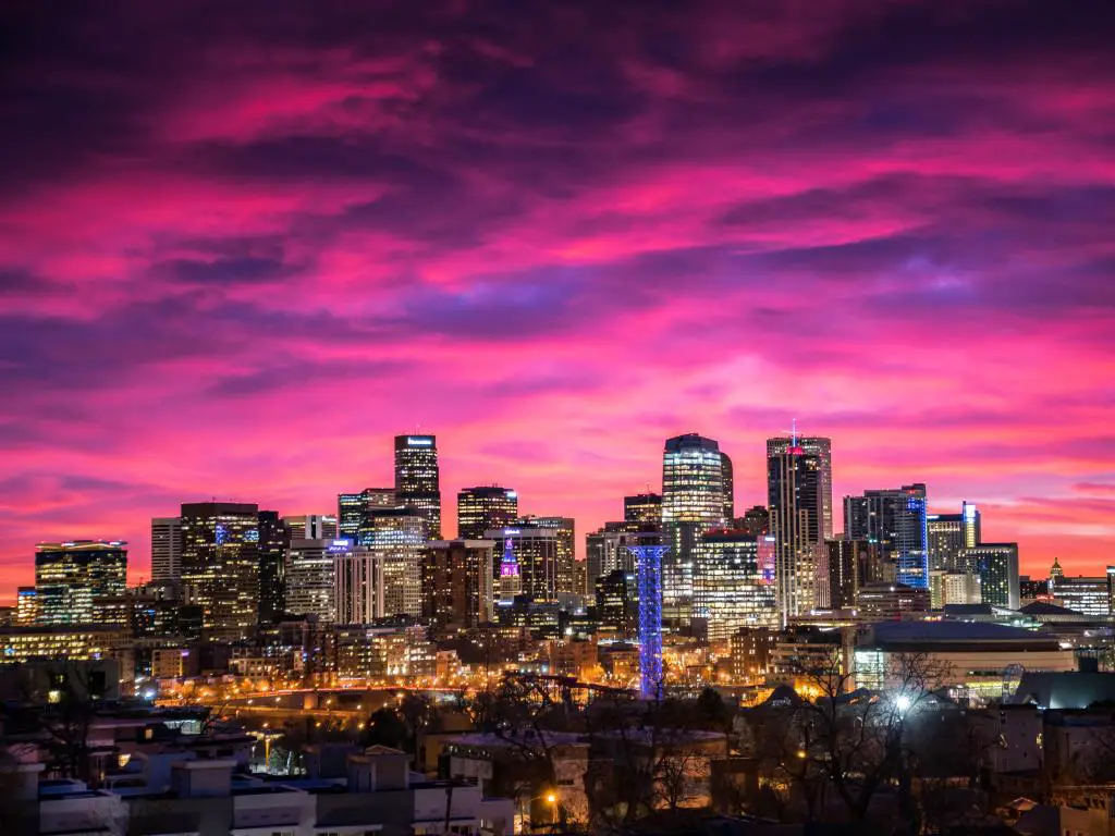 Denver, EE.UU. en el centro al amanecer bajo un cielo rosa con los edificios de la ciudad iluminados.