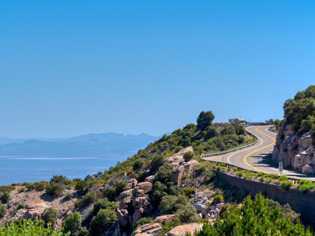 Un camino sinuoso a lo largo de la ladera de una montaña con rocas y vegetación, con una vista de largo alcance