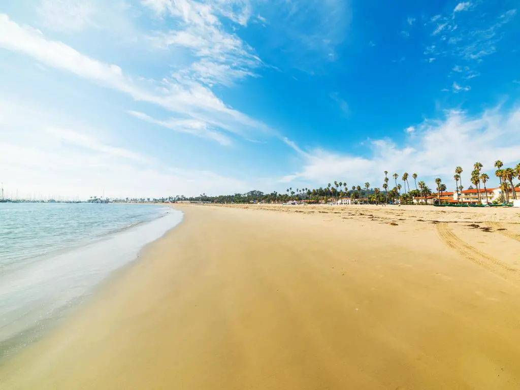 Costa dorada en Santa Bárbara, California, con árboles y casas de playa a la derecha y el mar a la izquierda.