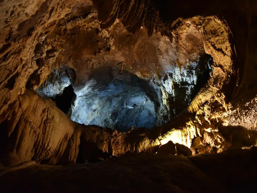 El interior de una cueva en el lago Shasta, con estalactitas, estalagmitas y depósitos de cal, además de un destello de luz que se filtra