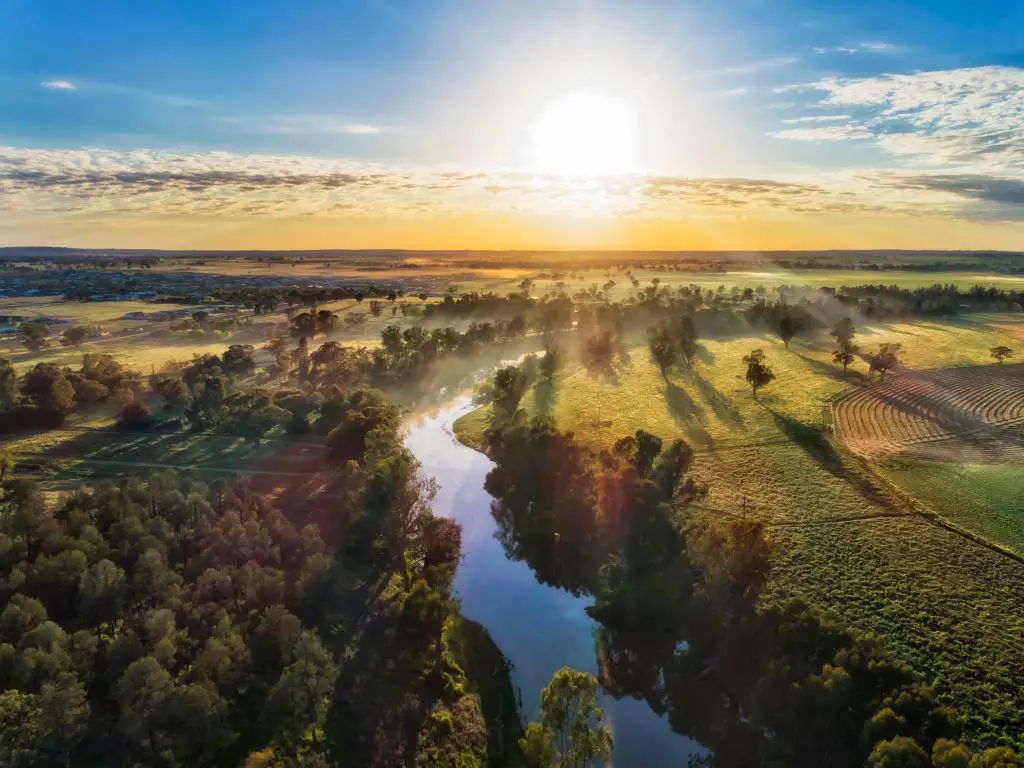 Río Macquarie, Dubbo en el centro con campos de cultivo a ambos lados y tomada como una toma aérea con el sol saliendo en la distancia. 