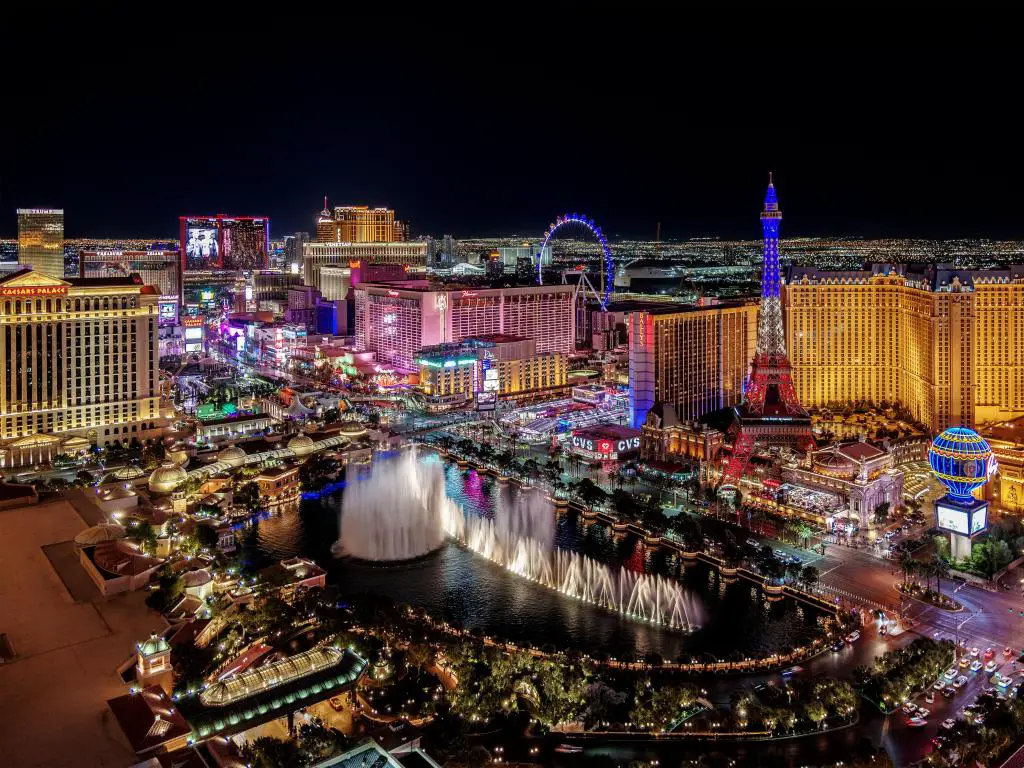 Una vista panorámica de Las Vegas por la noche que muestra fuentes de agua y edificios de la ciudad al fondo.