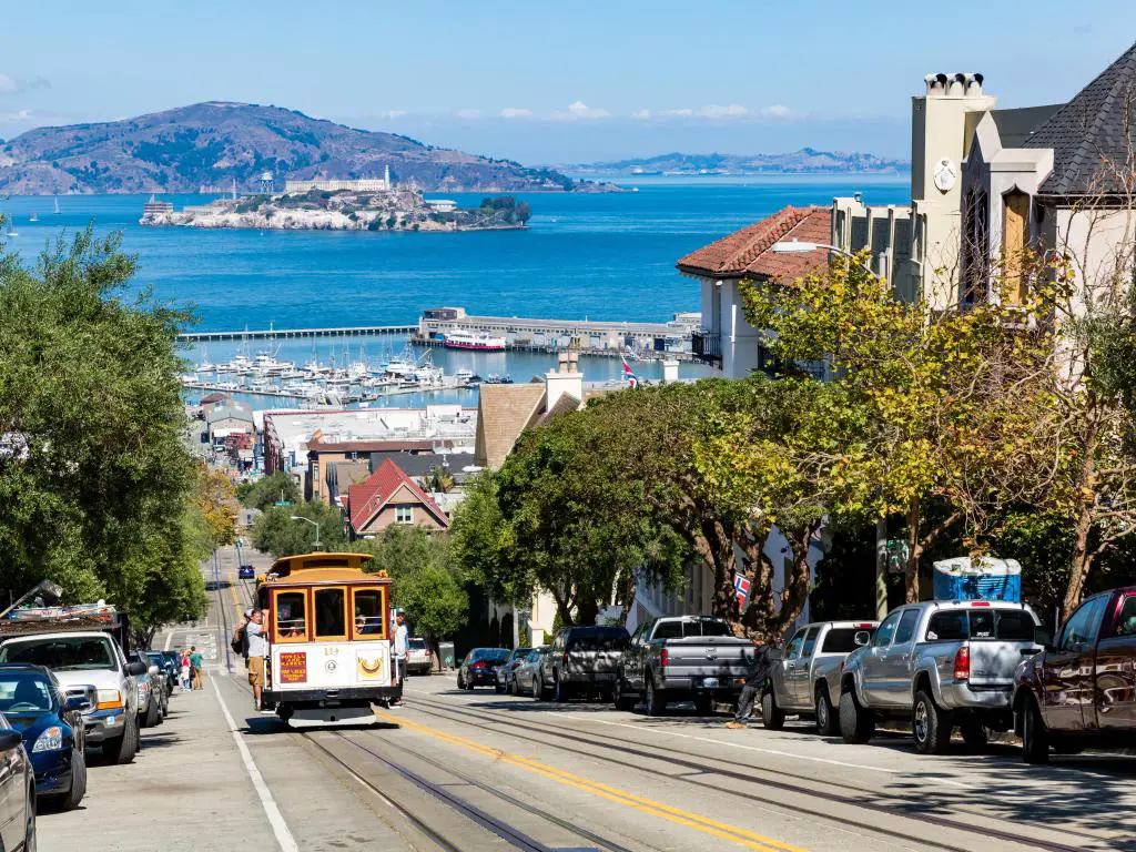 Calle San Francisco con un teleférico histórico que conduce cuesta arriba.  Día soleado con el mar de fondo