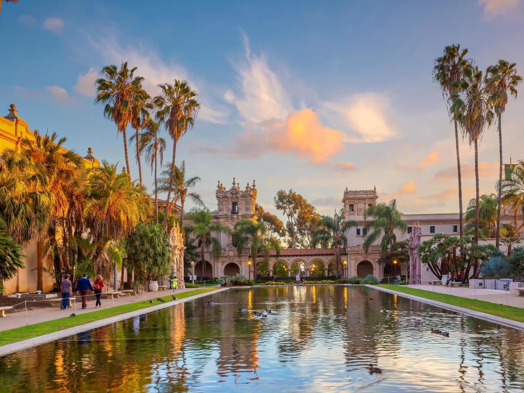 Parque público Balboa, San Diego al atardecer, con agua reluciente en primer plano y palmeras 
