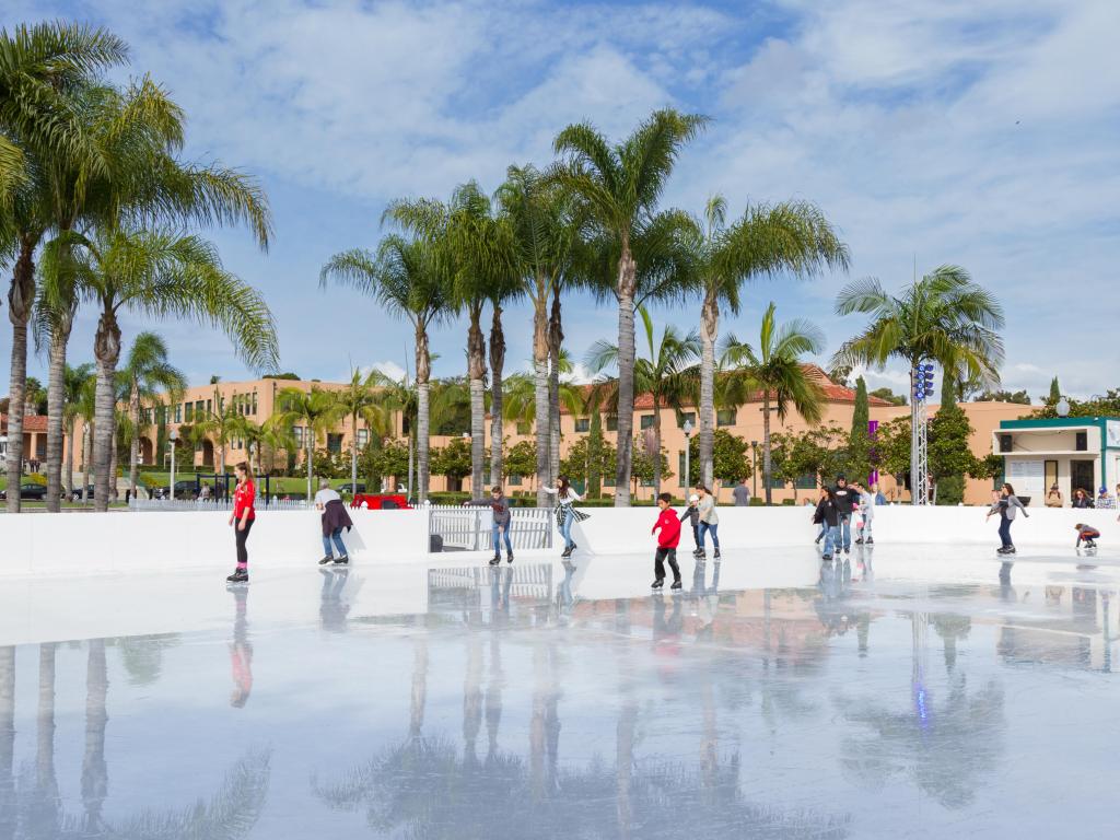 Gente patinando sobre hielo en el centro de San Diego en invierno con palmeras al fondo 