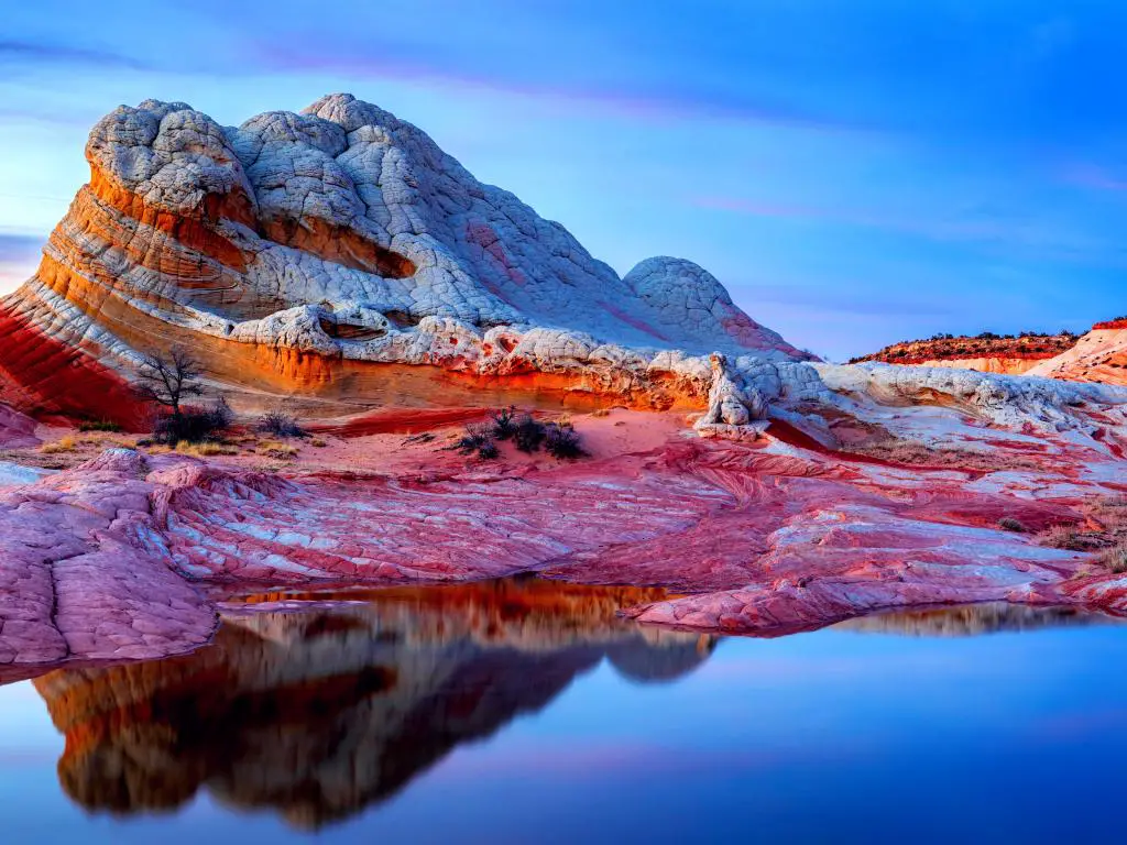 Un hermoso acantilado de arenisca, los bolsillos blancos y la formación rocosa del cañón rojo y blanco en forma de ola en los acantilados de Vermillion que reflejan el agua durante la puesta de sol