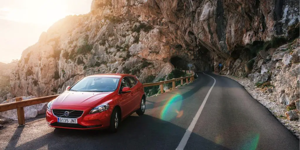 Un coche rojo circulando por la derecha en las montañas de España 