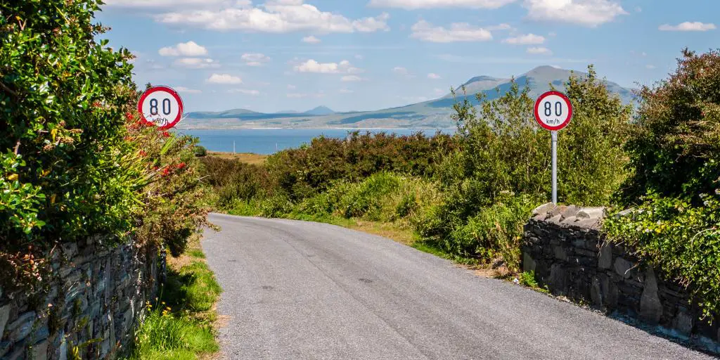 2 señales de límite de velocidad en una carretera rural con montañas de fondo en Irlanda 