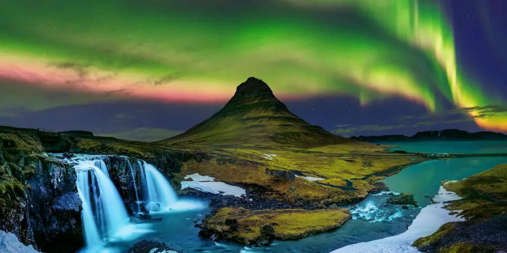 Aurora boreal en el cielo de Islandia sobre una cascada