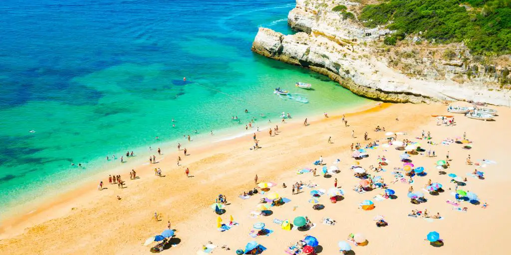 Gente relajándose en una playa de Portugal con el mar azul en la foto 