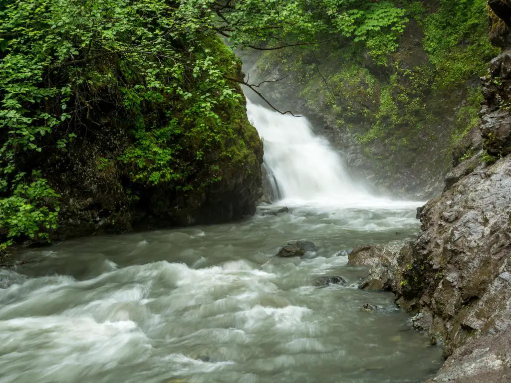 Thunderbird Falls en Alaska con rocas y árboles a ambos lados de la cascada. 