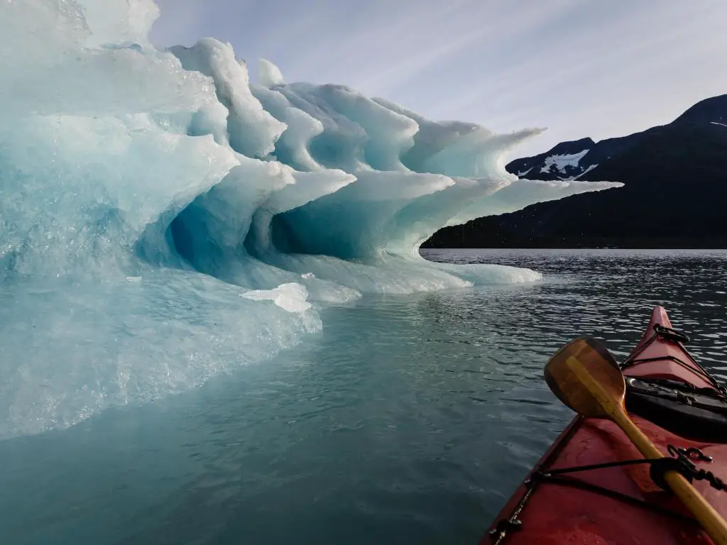 Paddler hace una pausa en el viaje para disfrutar del esplendor de las formas del iceberg que se derrite en verano en el Parque Nacional Kenai Fiords de Alaska