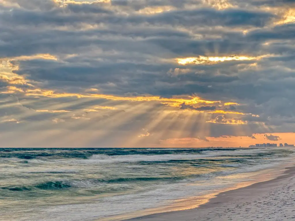 Santa Rosa Beach, Florida, EE.UU. con una espectacular puesta de sol de luz pastel con rayos de sol en el horizonte del paisaje urbano de la costa de Pensacola en Panhandle y el océano.