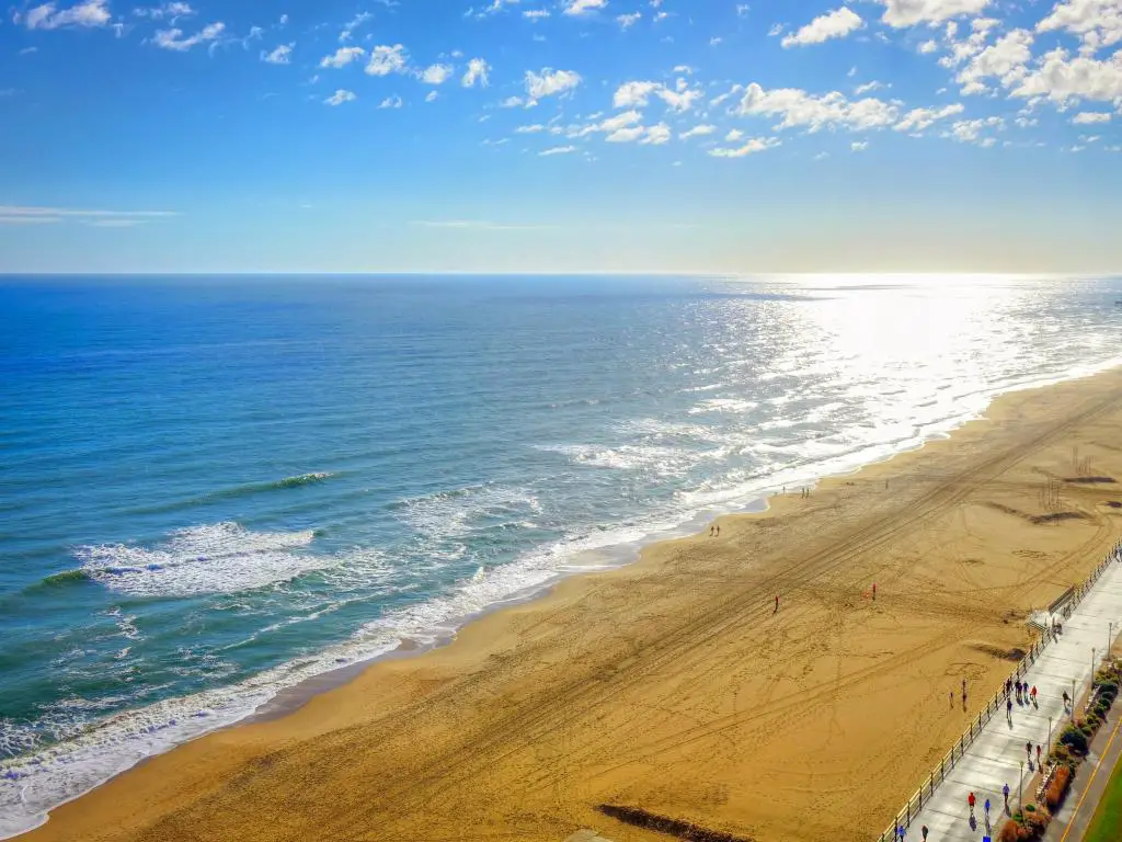 Virginia Beach, Virginia, EE.UU. con el paseo marítimo de la playa en primer plano y tomada como una vista panorámica aérea alta de la arena amarilla, mar tranquilo en un día claro y soleado.