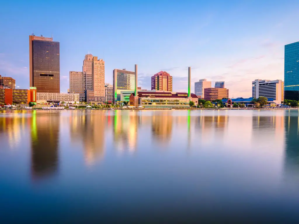 Toledo, Ohio, EE.UU. con el horizonte del centro de la ciudad en el río Maumee al atardecer reflejándose en el agua en primer plano.