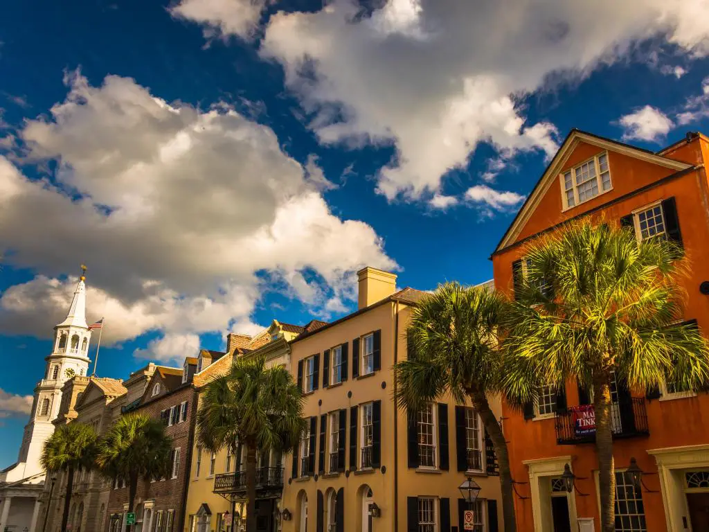 Edificios coloridos con persianas oscuras ornamentadas y palmeras en frente de Broad Street, Charleston