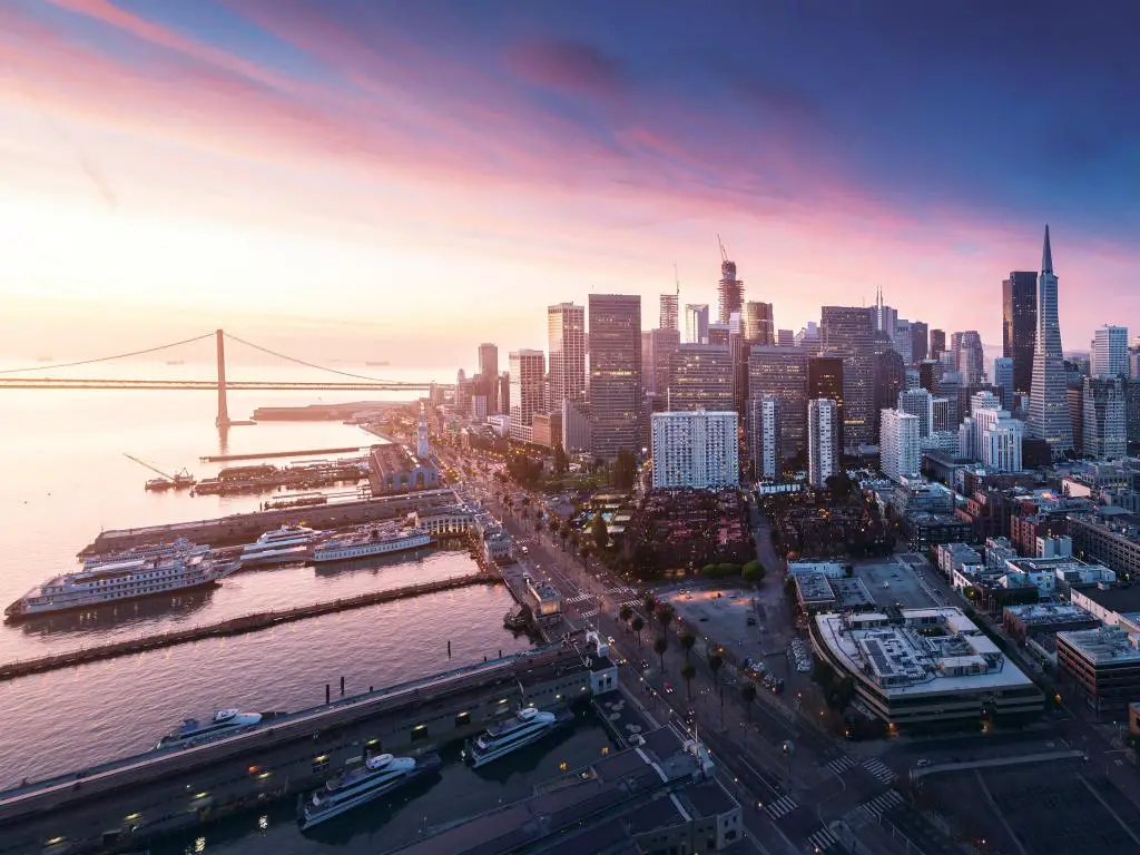 San Francisco, EE.UU. con una vista panorámica de la ciudad al amanecer con el paseo marítimo y el centro y el puente a lo lejos. 
