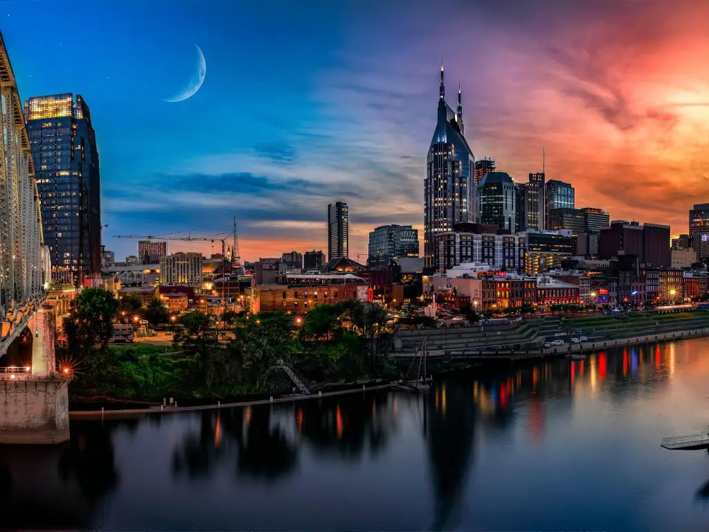 Nashville, Estados Unidos, tomada al atardecer con un cielo espectacular, el horizonte de la ciudad a lo lejos y el río en primer plano. 