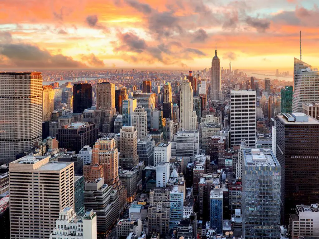 Nueva York, Estados Unidos al atardecer con los rascacielos en primer plano y el cielo en rojo, amarillo y naranja. 