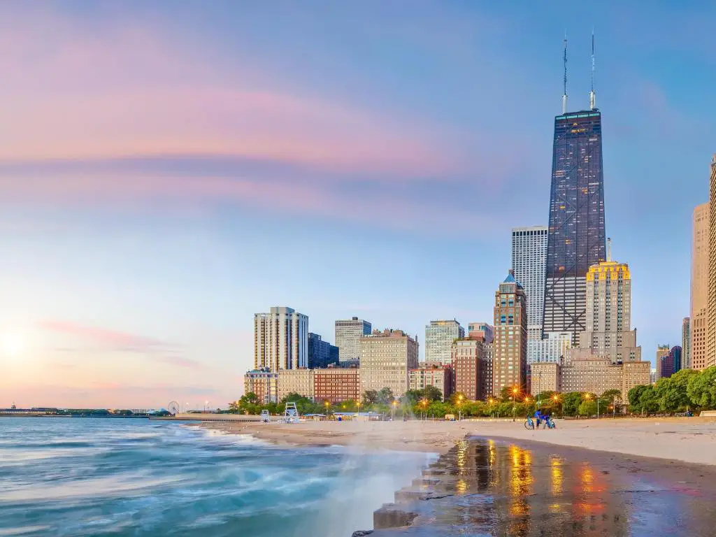 Chicago, Illinois, EE.UU. con el horizonte del centro de la ciudad al fondo al atardecer y la orilla del lago Michigan en primer plano.