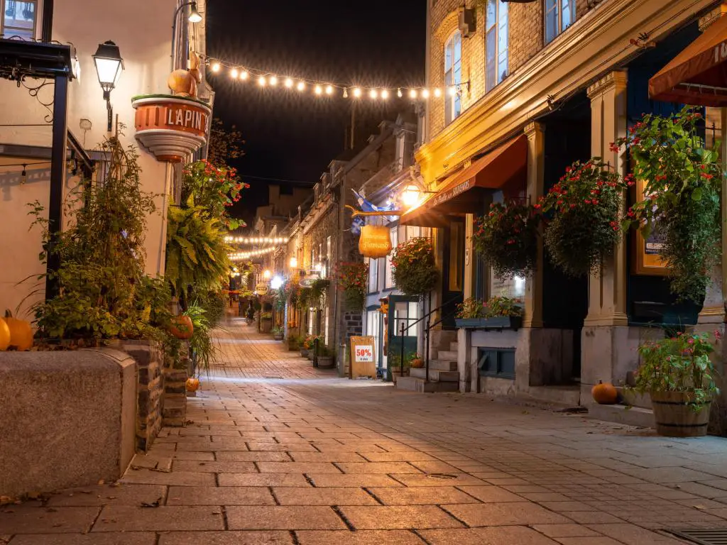 Quebec, Canadá, con una vista nocturna del Quartier du Petit Champlain en otoño con bonitas tiendas a ambos lados de una calle adoquinada.