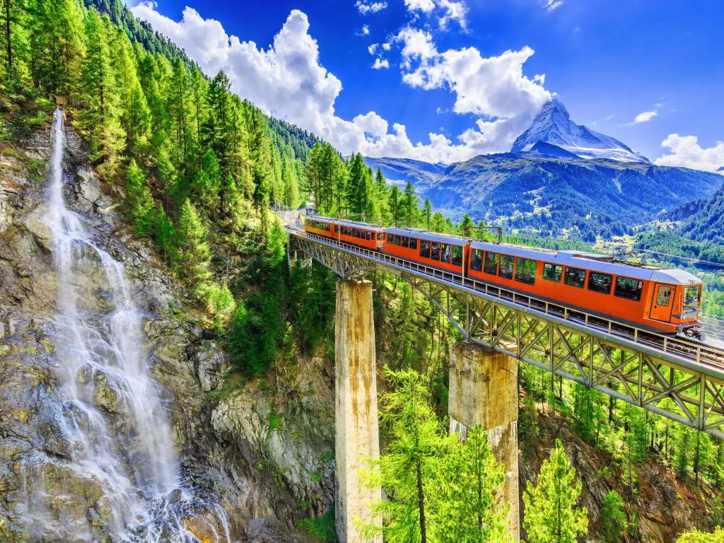 Zermatt, Suiza.  Tren turístico Gornergrat con cascada, puente y Matterhorn.  región de Valais.