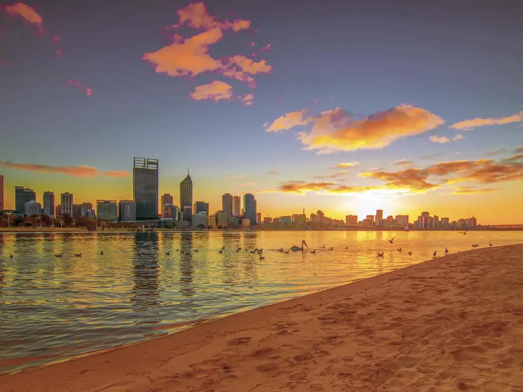 Paisaje de la ciudad de Perth con el mar y la playa enfrente demostrando ambos lados de Perth, al atardecer