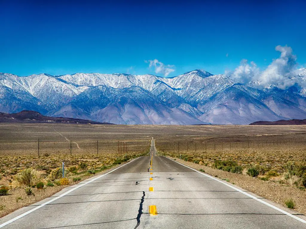 Un camino reseco que atraviesa las montañas nevadas de Sierra Nevada en California