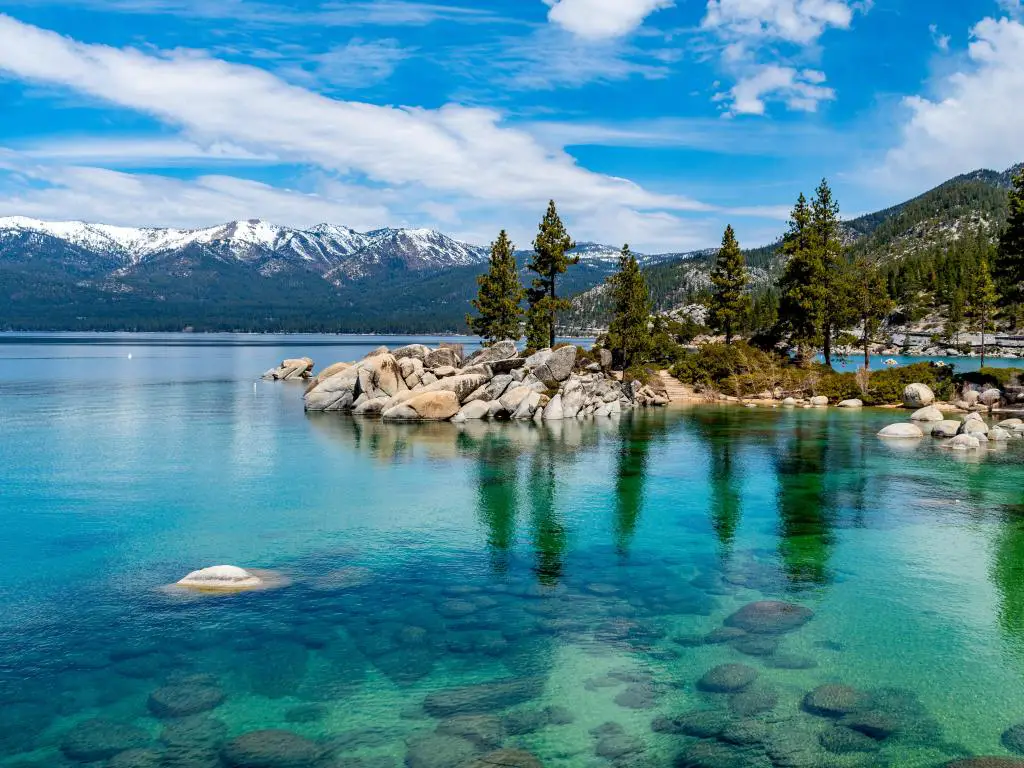 Aguas cristalinas del lago Tahoe rodeadas de árboles altos y delgados y picos montañosos
