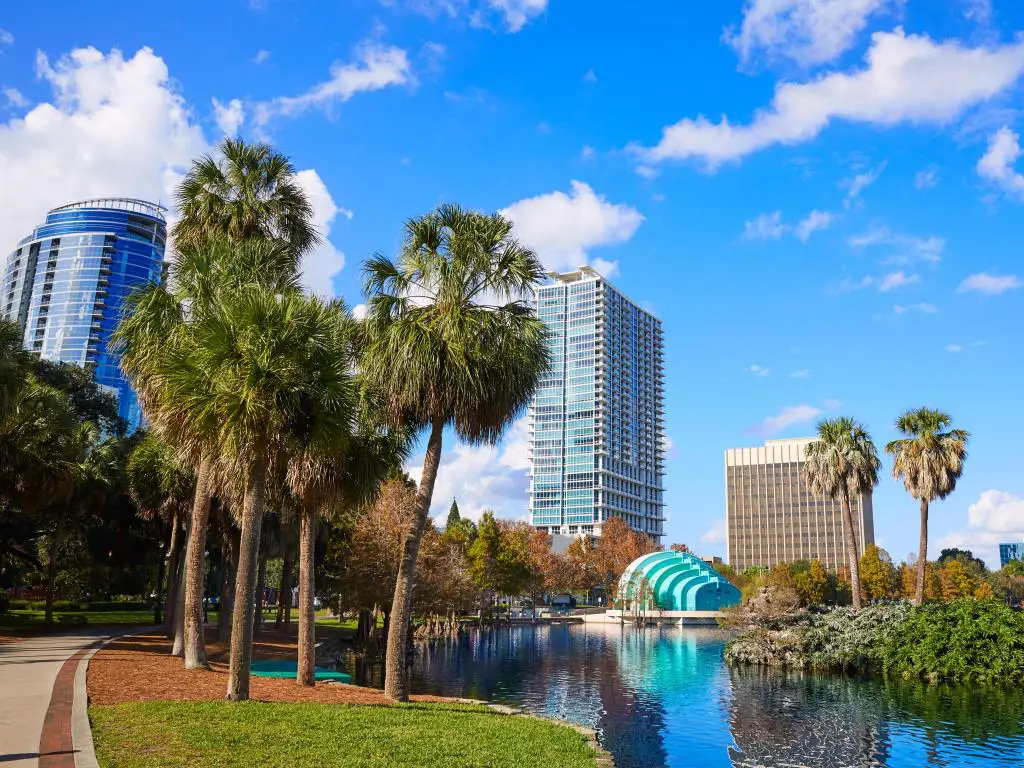 Orlando, Florida, EE.UU. con el horizonte de la ciudad al fondo y el lago Eola en primer plano, con hierba y palmeras y tomada en un día soleado.