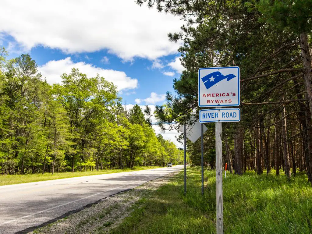 El cartel de desviación de River Road America al lado de la carretera a lo largo del Bosque Nacional Manistee en un día nublado