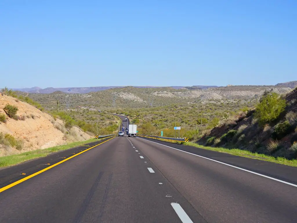 Interestatal 17 en Arizona con varios autos y camiones conduciendo por la carretera disfrutando de la vista de las montañas y los árboles verdes 
