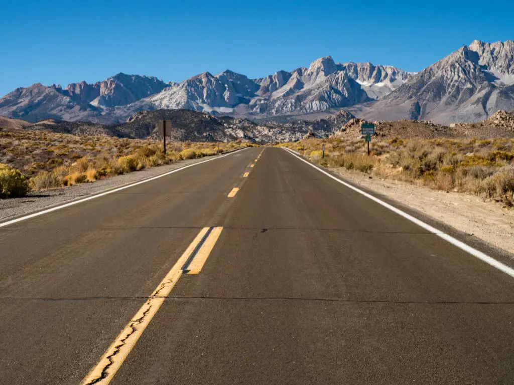 Un día soleado en una carretera vacía al Bosque Nacional Inyo con una gran vista de las montañas del este de Sierra Nevada.