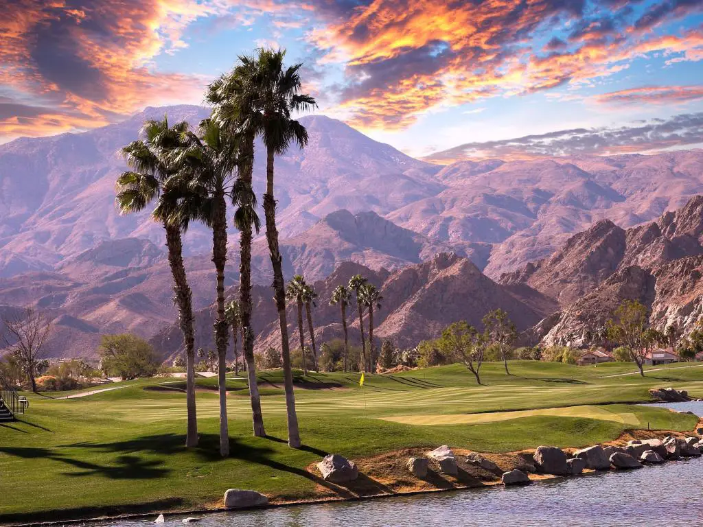 Palm Springs con un campo de golf y un lago en primer plano, palmeras y montañas al fondo.
