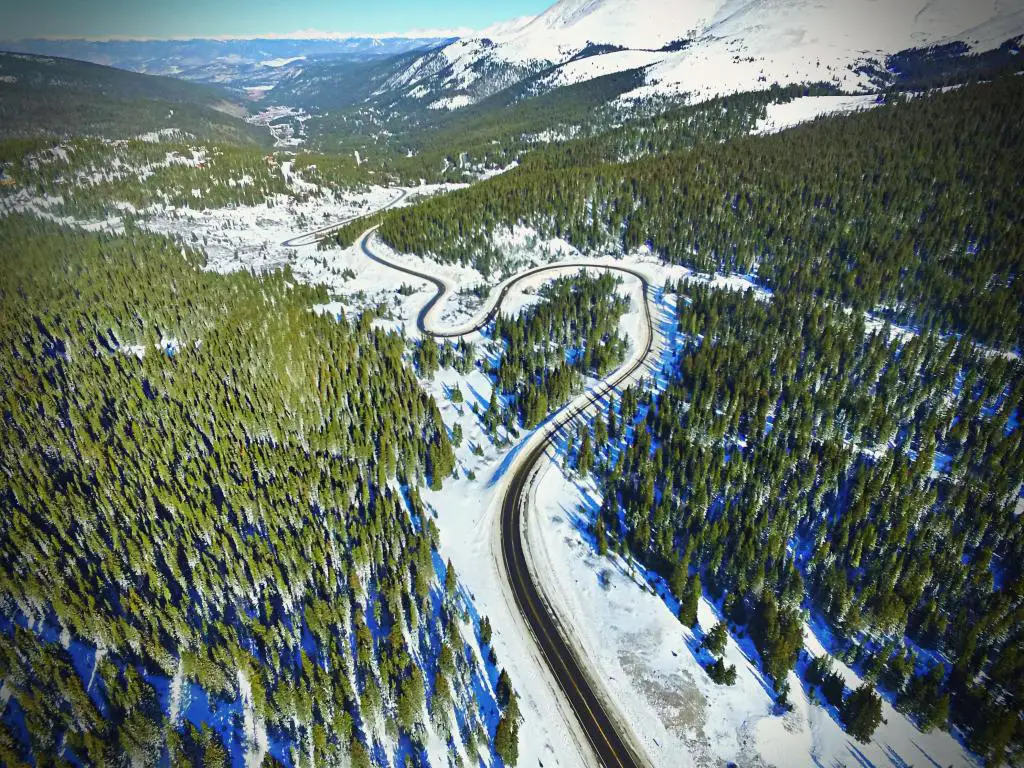 Vista aérea de la carretera ventosa de Hoosier Pass a través de las Montañas Rocosas cerca de Breckenridge, Colorado, con la carretera atravesando un bosque nevado